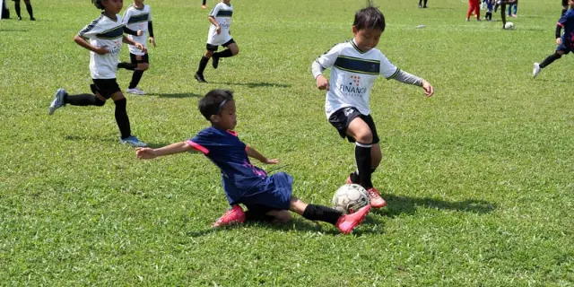 Children playing football on a grass field