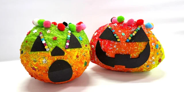 Two jack-o’-lantern crafts decorated with pompoms and sequins